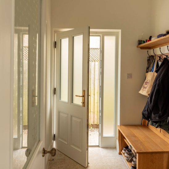 Engineered timber 'Kingston' entrance door, with Newbury aged brass door handle and obscured glass. White on the inside to match the interior, green on the outside.