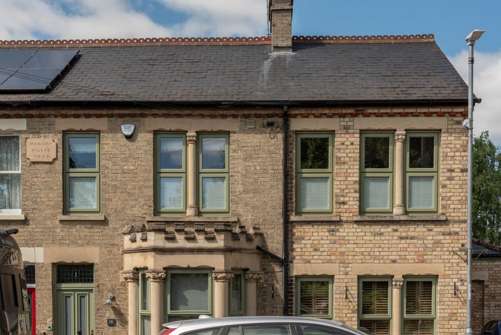 Picture of front of traditional terraced house renovated with new green timber windows. 