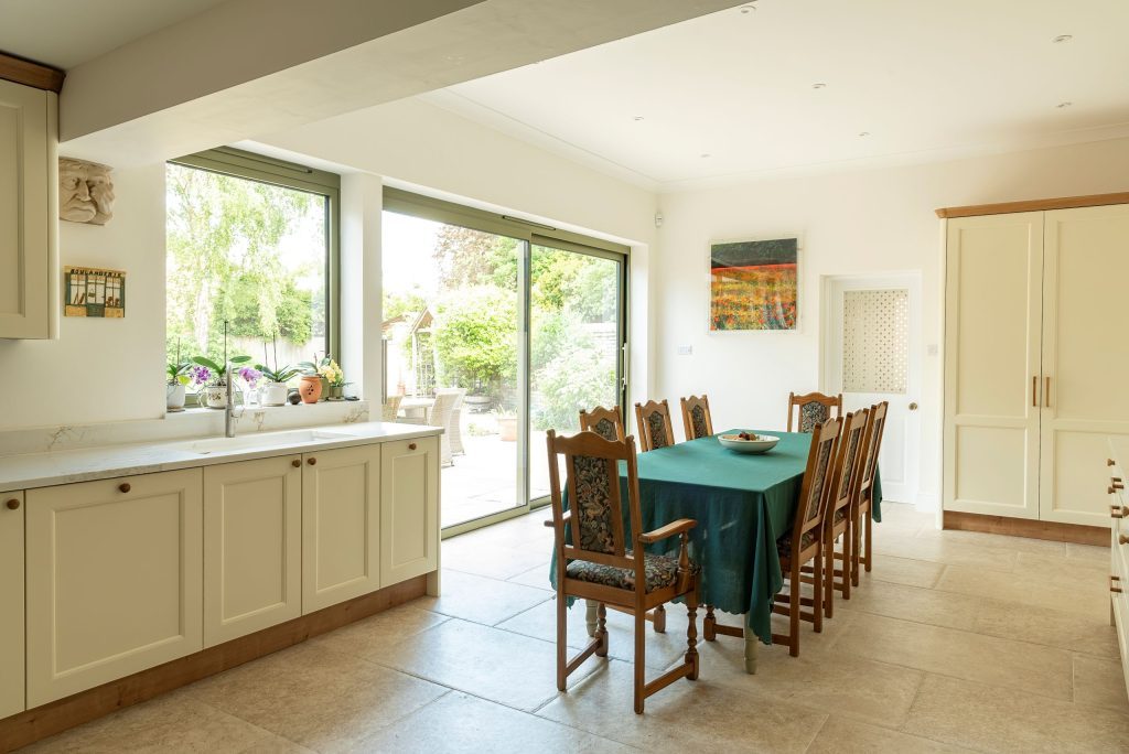 Country kitchen with green slimline sliding doors and matching green aluminium window. 