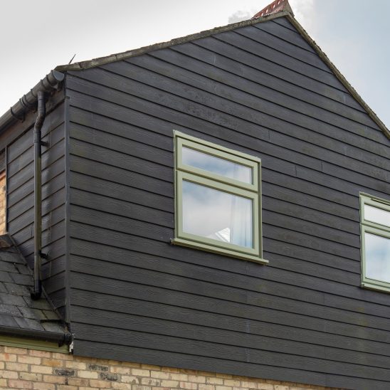 Engineered timber casement windows in Green against black timber cladding