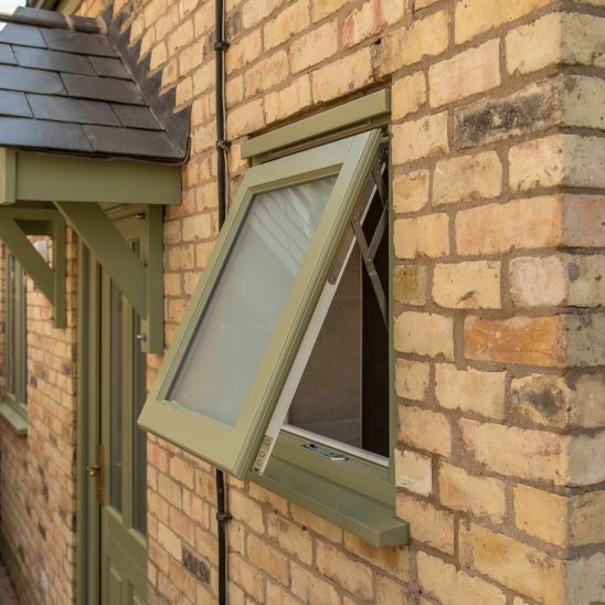 Engineered timber casement windows, and Kingston door in Green with a Newbury aged brass door handle