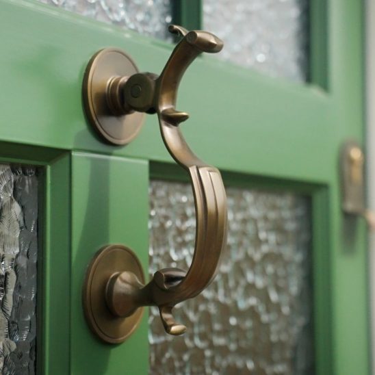 Doctors door knocker on green timber entrance door with matching escutcheon and textured glass