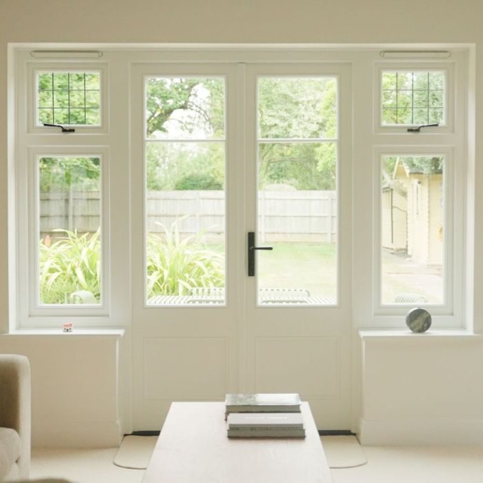 white timber front doors with side windows leading out to a traditional garden.