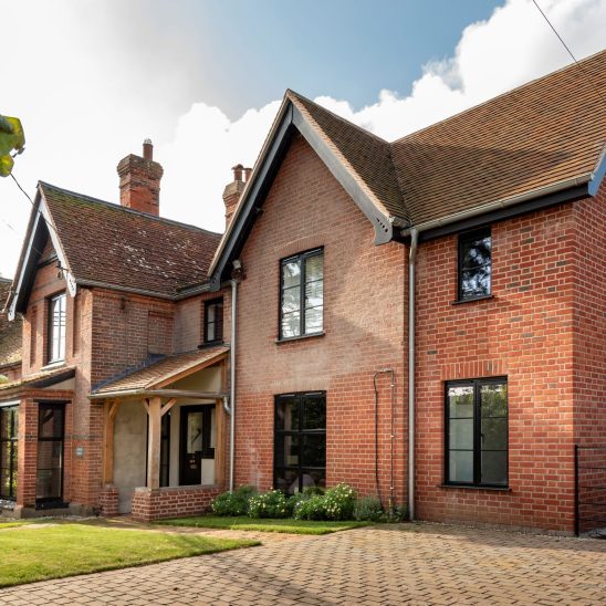 Red brick house with Art Deco black aluminium windows and patio doors