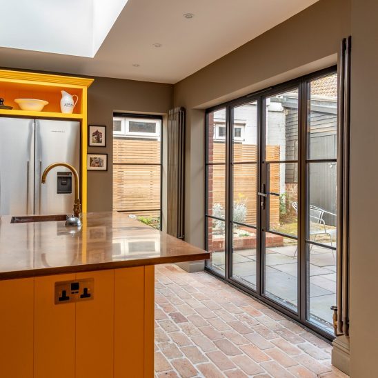 Contemporary kitchen with black aluminium heritage glazing and Patio doors featuring ultra slim glazing bars in Orford home