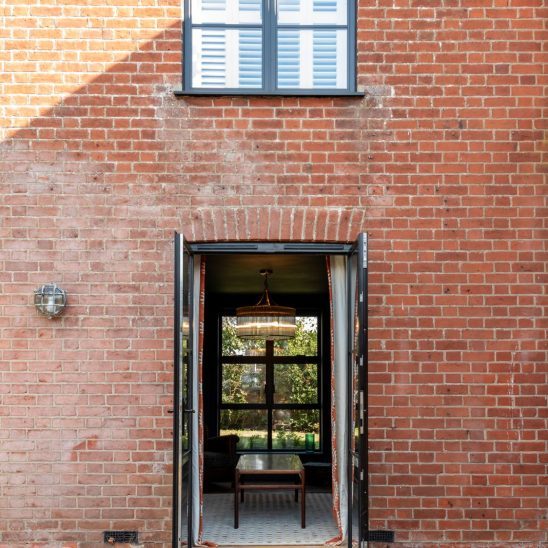 Red brick house with Art Deco black aluminium windows and patio doors