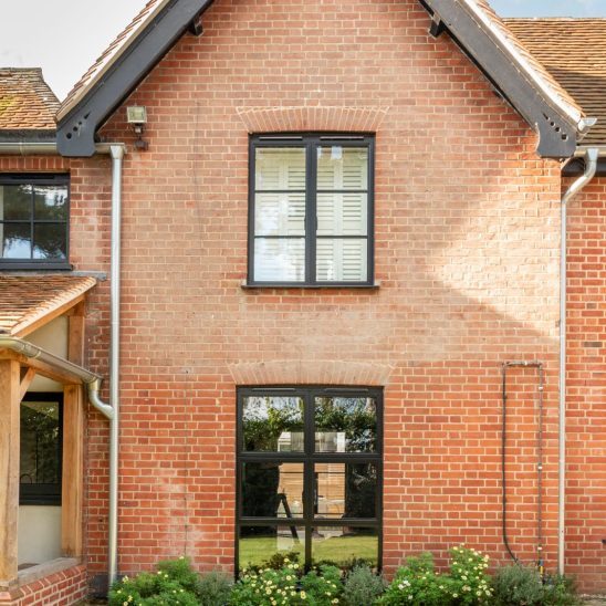 Red brick house with Art Deco black aluminium windows and patio doors