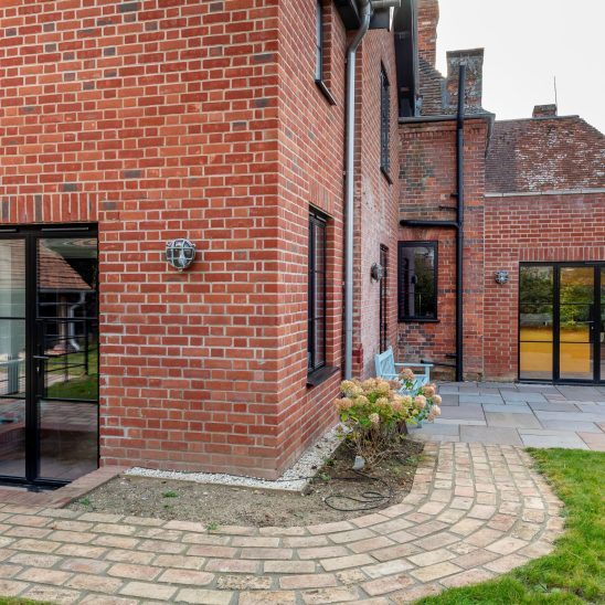 Red brick house with Art Deco black aluminium windows and patio doors
