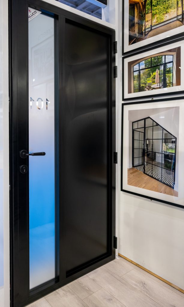 picture of black steel look front door in an exhibition with propery pictures on the wall behind