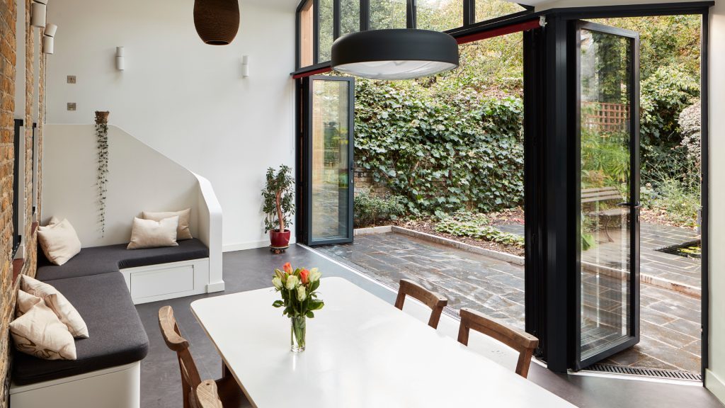 Open bifold doors with matching single door inside a dining room and patio area